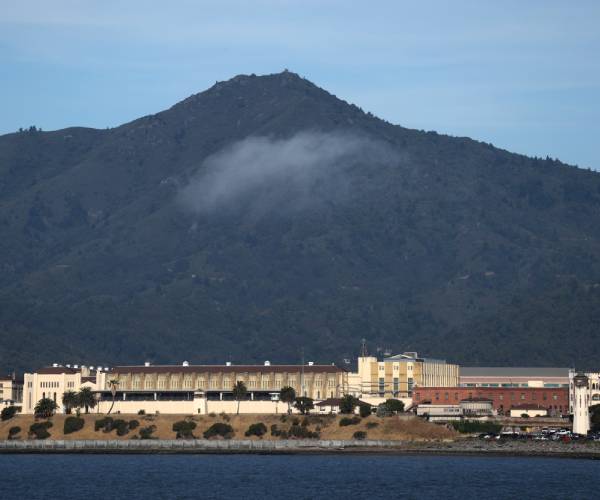 exterior of the prision with water in front and a mountain in the back