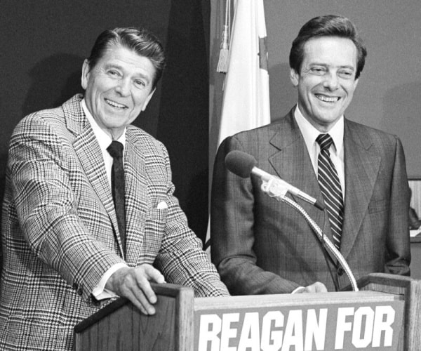 ronald reagan stands at a reagan podium with bill brock smiling next to him.