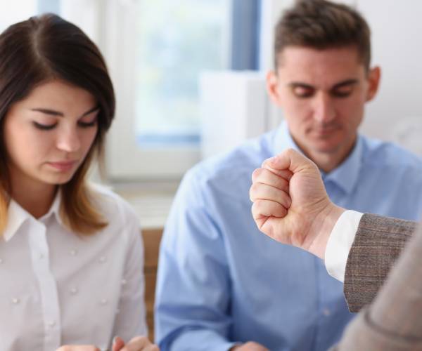 a female and a male employee being intimidated by a man in a suit shaking his fist at them