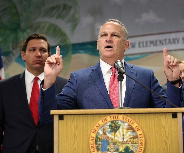 ron desantis listens to richard corcoran speak