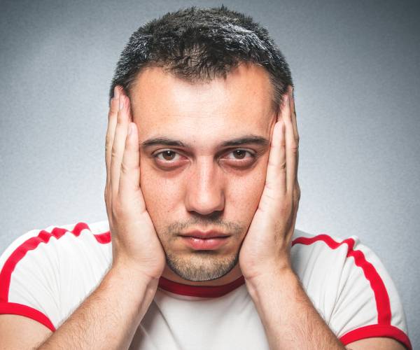 a man with his hands on the sides of his face showing frustration