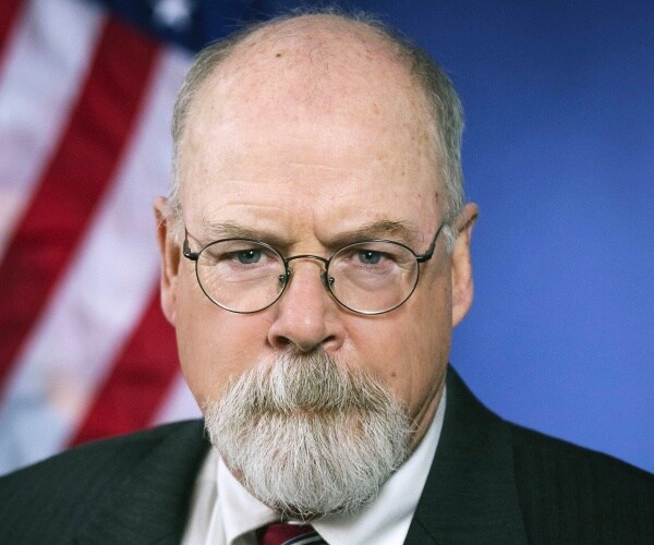 closeup of john durham with glasses and flag in background