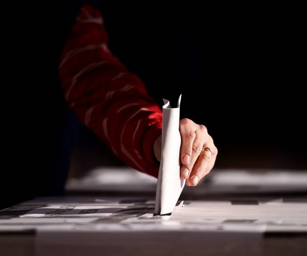 hand places ballot in box