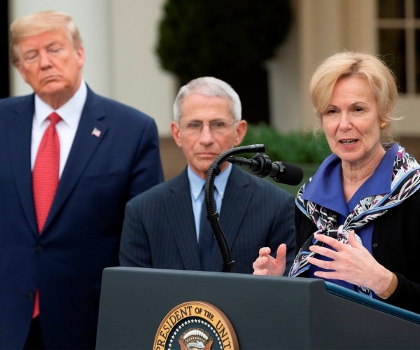 birx in a black sweater and patterned scarf speaks at the podium outside with trump and fauci standing nearby