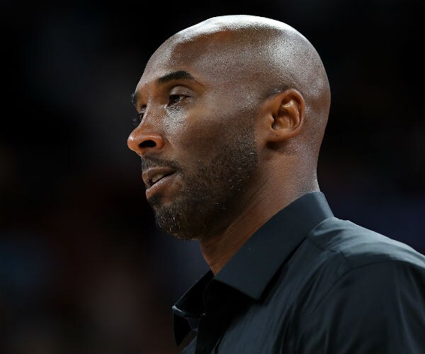 the late kobe bryant looks to the left while standing at an en bee ay game