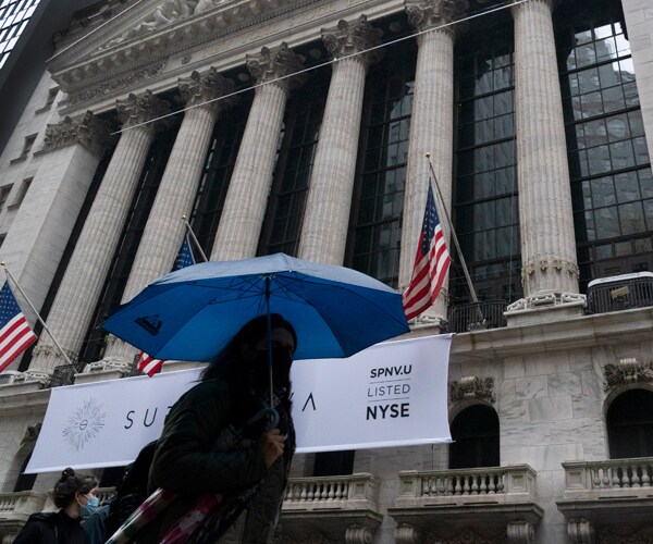 a woman walks past the new york stock exchange holding an unbrella