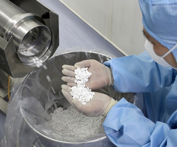 a worker in china holds chloroquine phosphate at a pharmaceutical factory