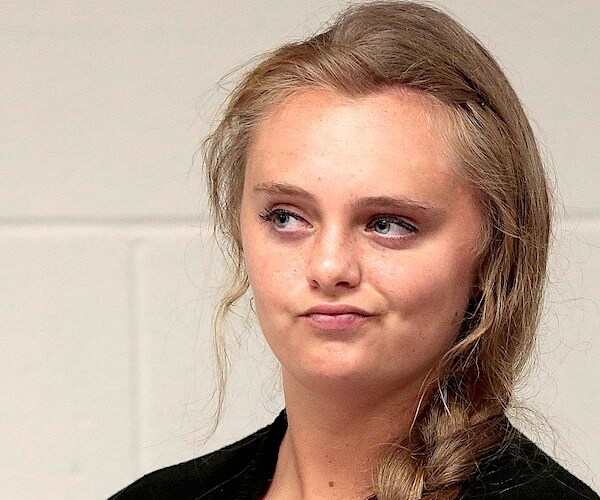 a teenage blonde girl gives a nonplussed expression while awaiting a judge's instructions in court