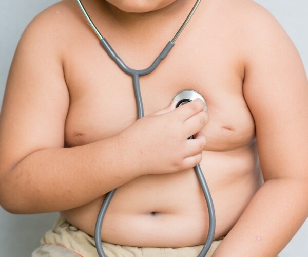 obese boy holding stethoscope to chest