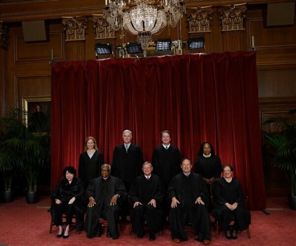 justices of the us supreme court pose for their official photo in black robes with cranberry background 