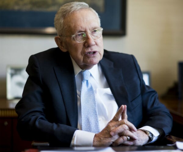 former senate majority leader harry reid speaking, dressed in dark suit, dress shirt and blue and white tie