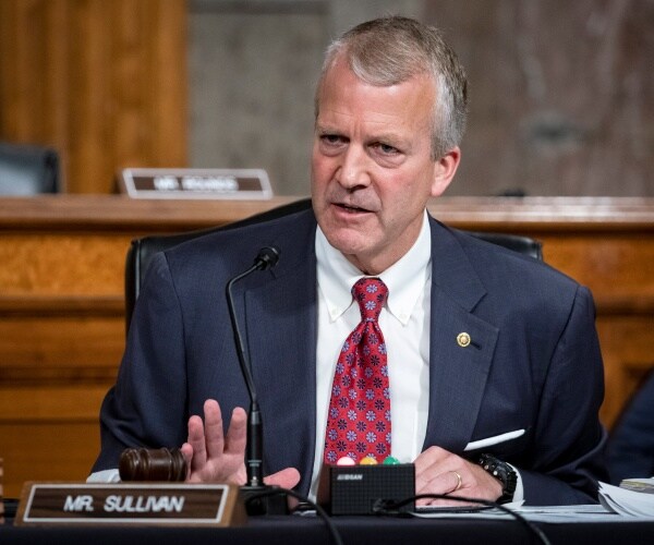 dan sullivan sits behind desk