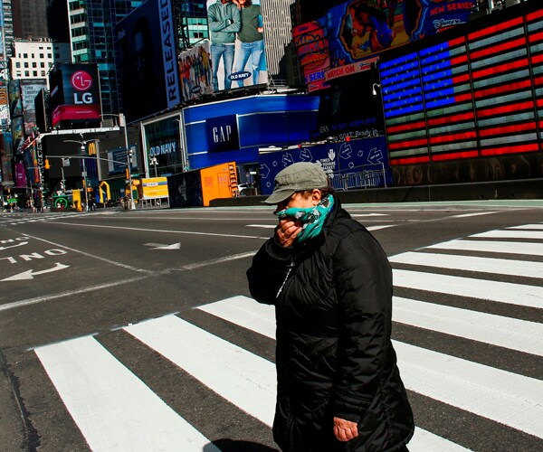 a woman covers her face as she walks in new york city's times square