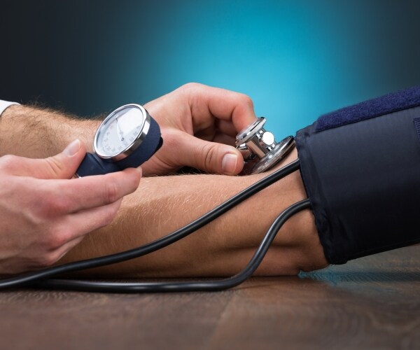 doctor checking blood pressure of patient at table