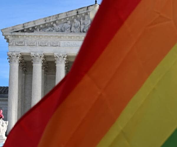 a gay pride flag flying in front of the united states supreme court building