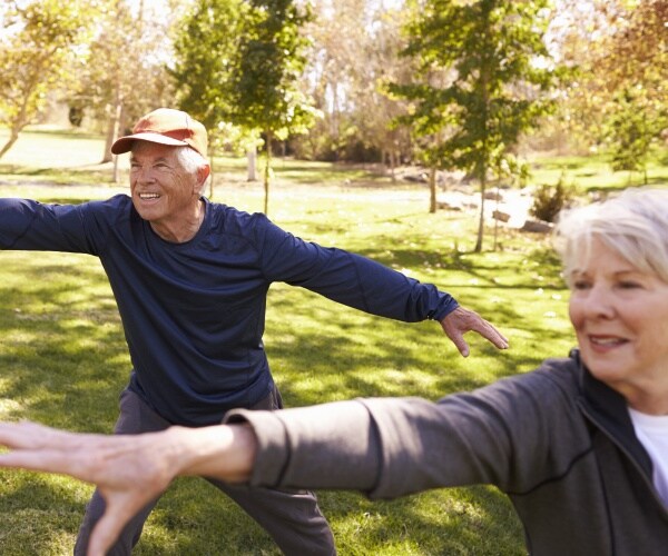 older man and woman doing tai chi in a park