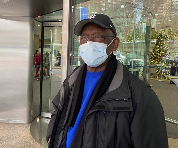 man wearing mask waits outside hospital in New York City