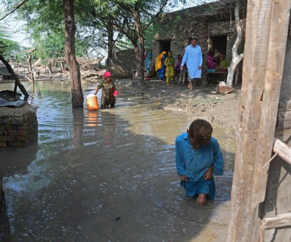 people gather outside their flooded houses