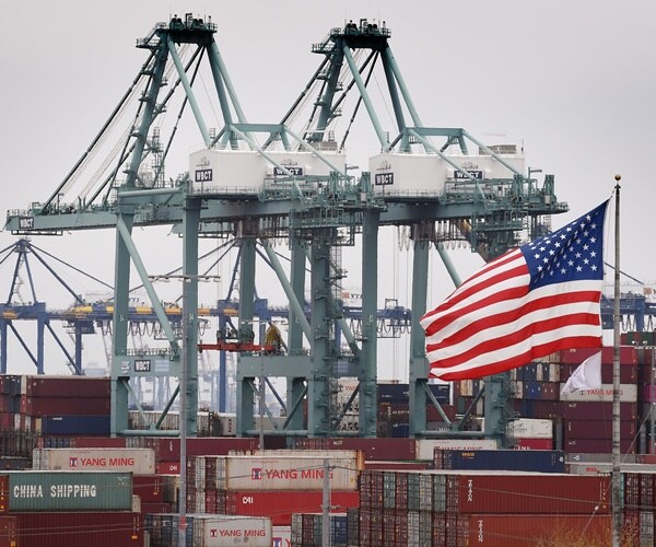 shipping containers in a u.s. port with the american flag overhead