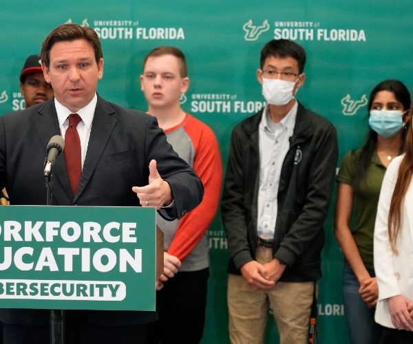 desantis at a podium with students behind him some masked and some unmasked