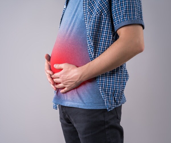 man holding stomach, highlighted in red, with abdominal bloat