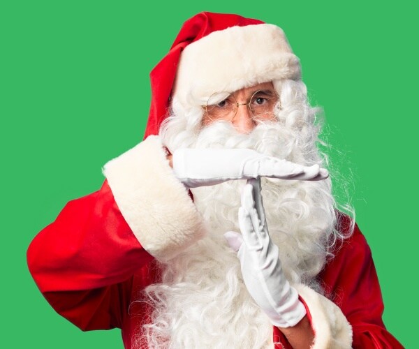 man dressed up in Santa costume with green background with hands in time out gesture