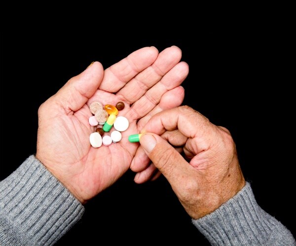 hand of older man holding a variety of pills