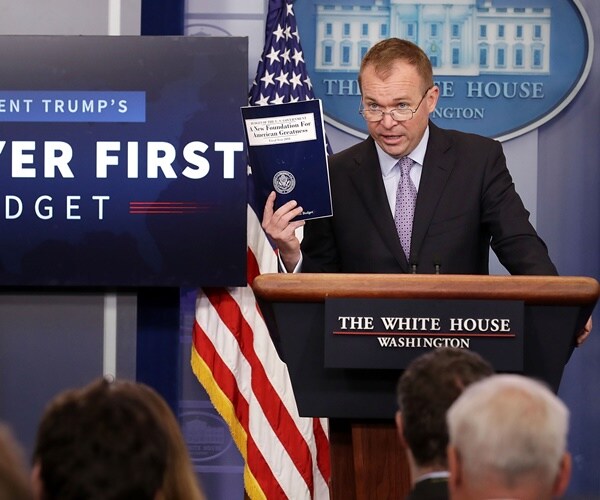 mick mulvaney holds a budget packet in his hands and speaks to the press corps from the podium