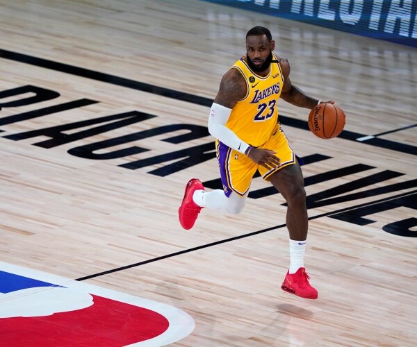 james in a yellow lakers jersey controlling the ball with BLM painted on the court