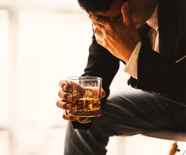 man looking depressed with liquor in glass in hand