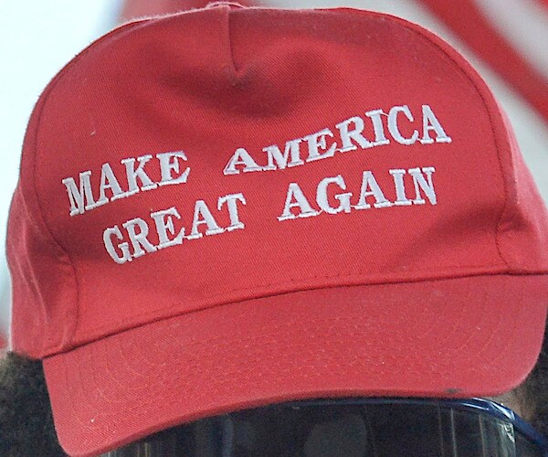 a red baseball cap reads make america great again in white letters