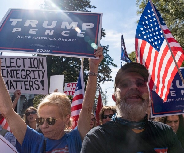 trump supporters hold trump signs and us flags