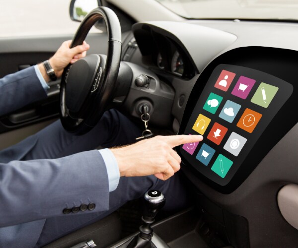 a driver pointing to an icon on an onboard car computer