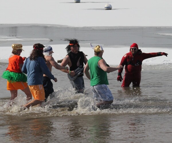 men and women dressed in costumes jumping into freezing cold water