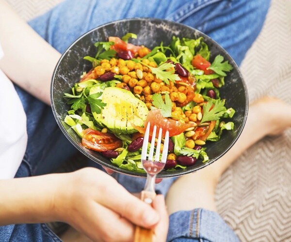 woman eating a vegan salad in a bowl