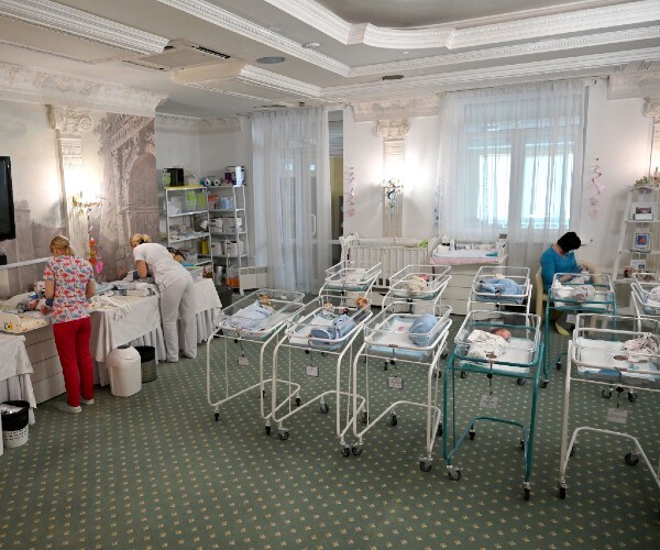 rows of babies in a room as nurses care for them