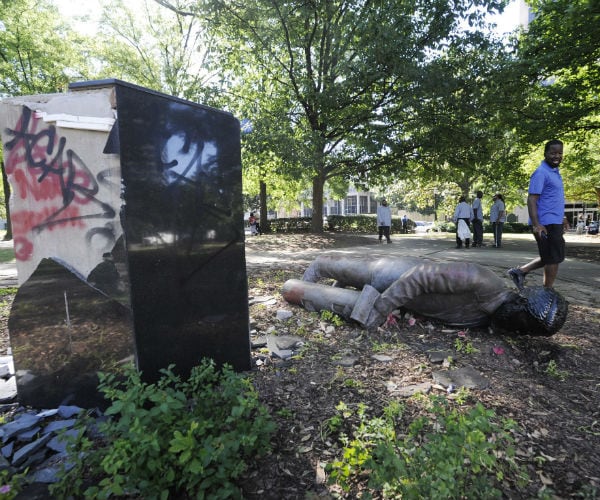 A man walks past a toppled statue of Charles Linn in Birmingham.