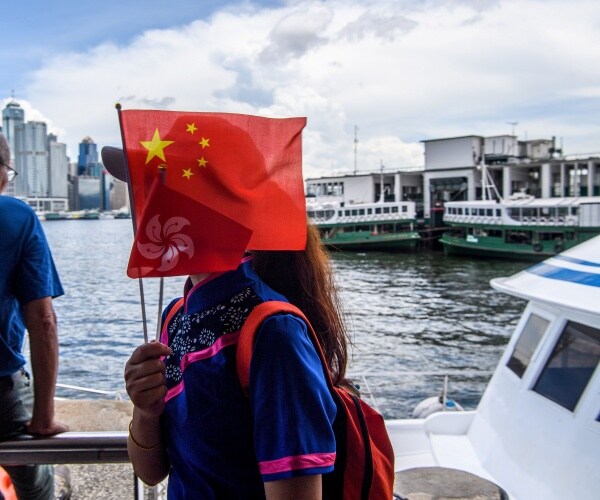 girl wearing a blue dress holds chinese and hong kong flags 