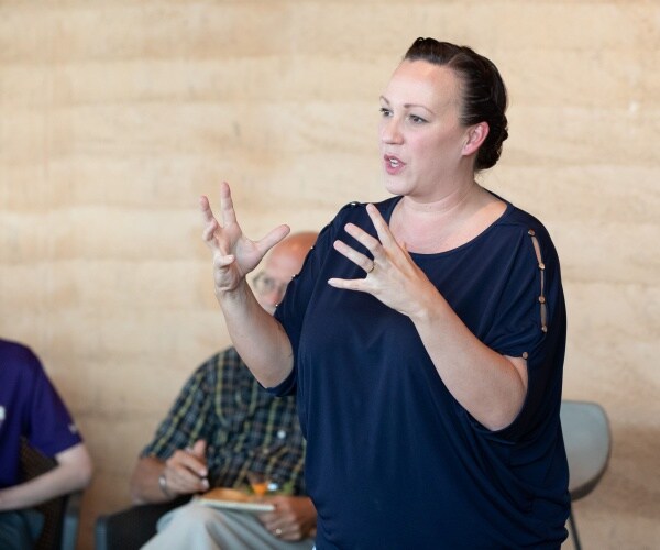 mj hegar in a navy blue top speaking to voters