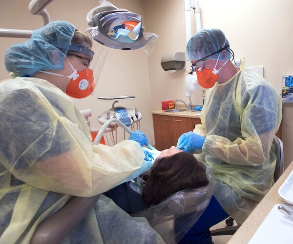 a dentist and a dental assistant work on a patient in virginia