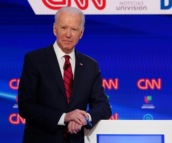 joe biden leans on a podium before a debate