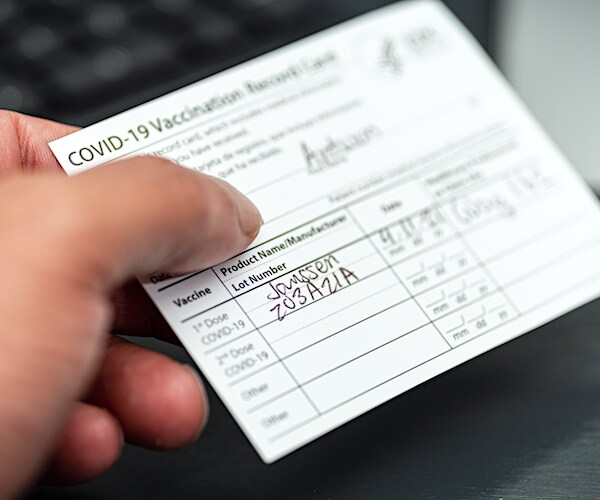 a man holds a proof of vaccination card