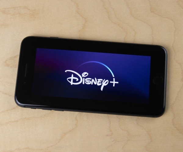 disney  logo is shown on a smartphone on a wood table