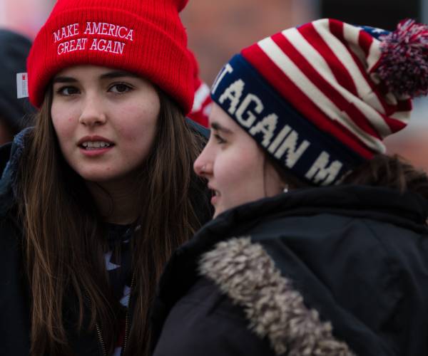 two young women wearing make america great again winter hats