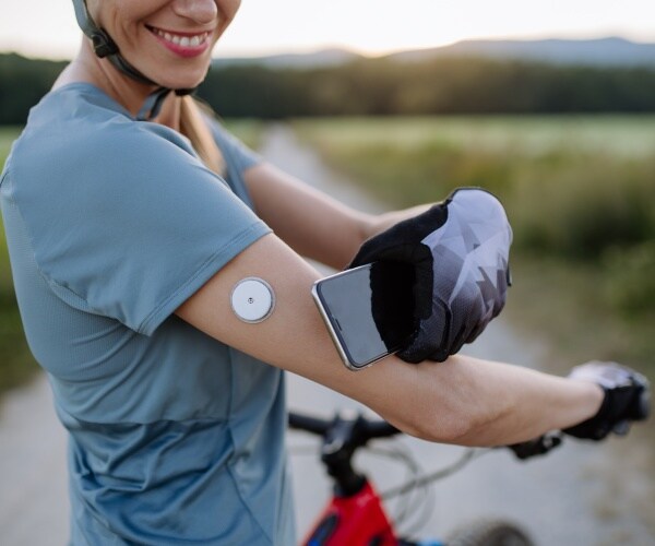 woman cyclist with a continuous glucose monitor patch on her arm