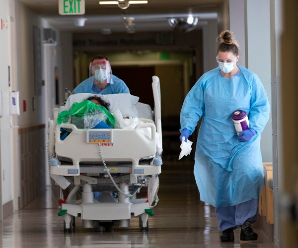 healthcare workers in a seattle hospital move a patient to a covid-19 unit