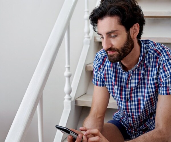 man sitting on stairs holding cellphone