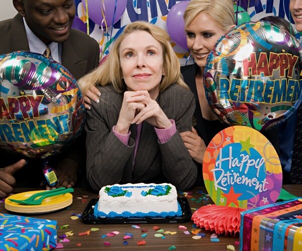 woman in middle in front of cake, with co-workers around, retirement celebration