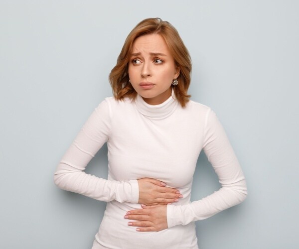 woman looking scared, in pain, holding stomach