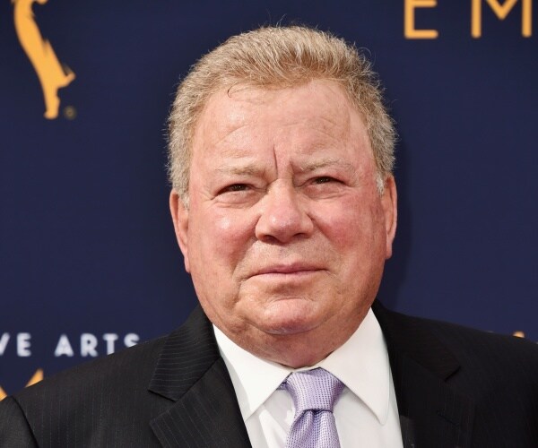 shatner in a black suit and light purple tie